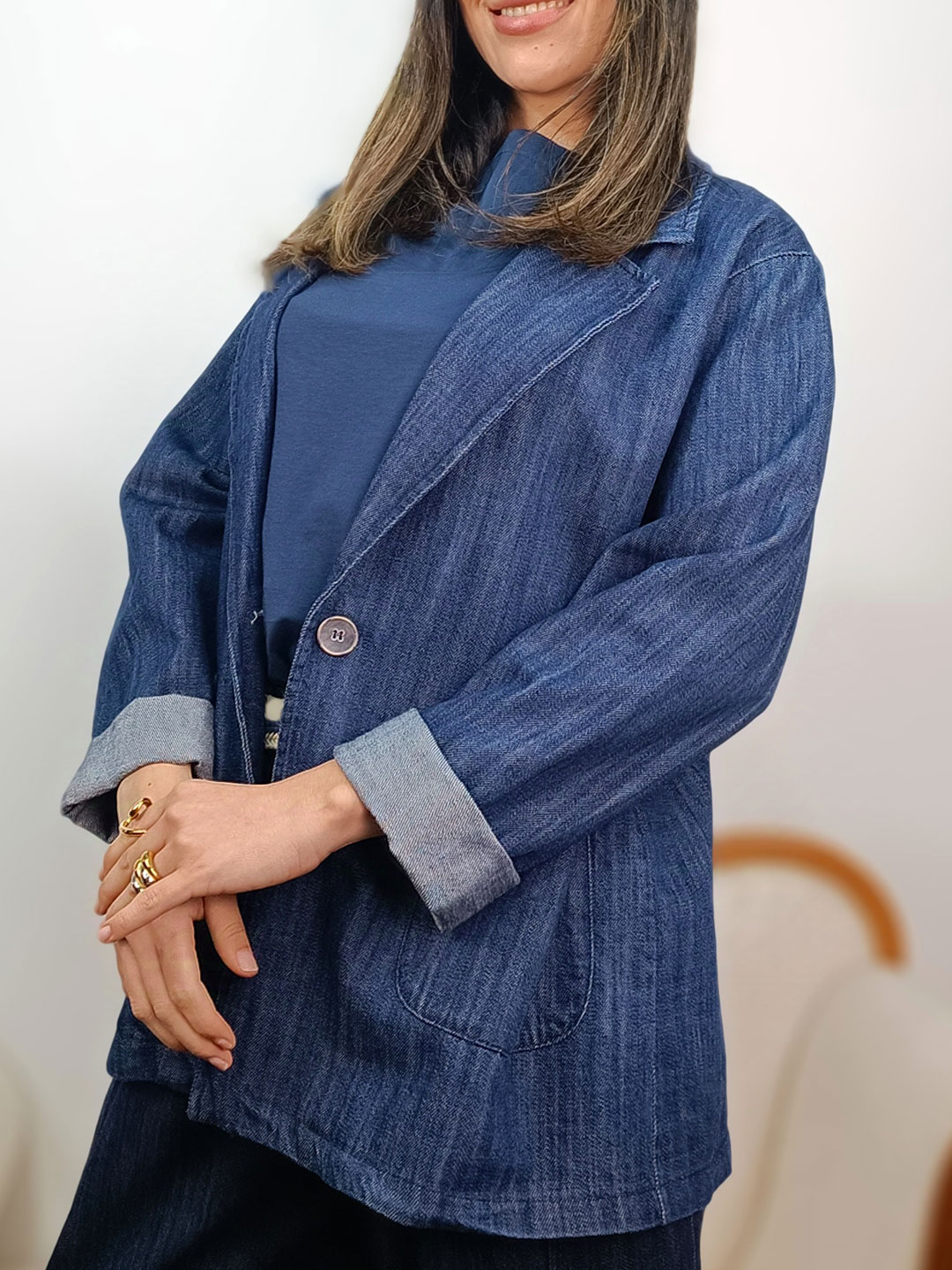 Perfil de blazer denim azul fluida con detalle de puño remangado.