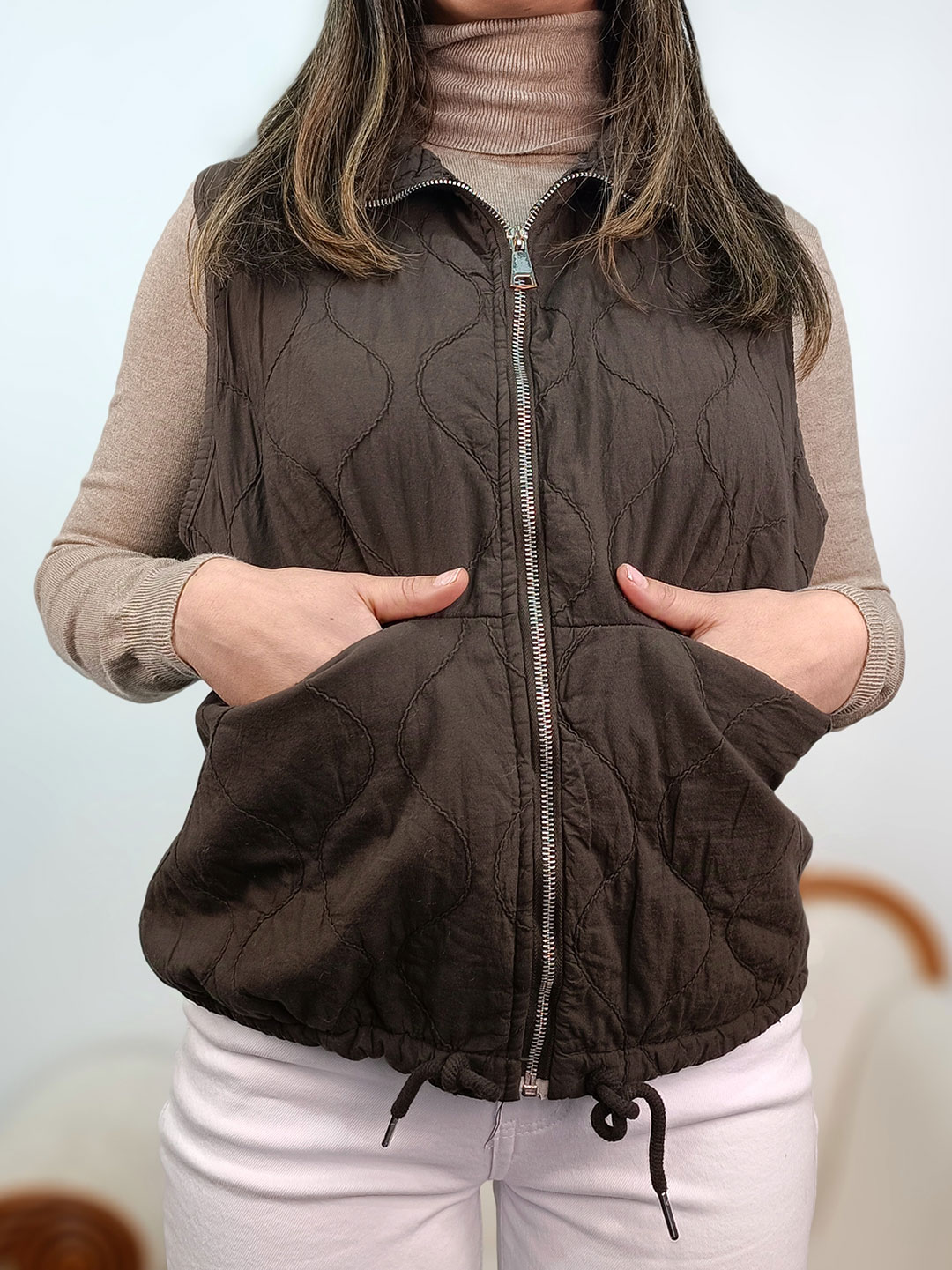 Detalle de la textura aguatada y cremallera del chaleco marrón chocolate mujer.