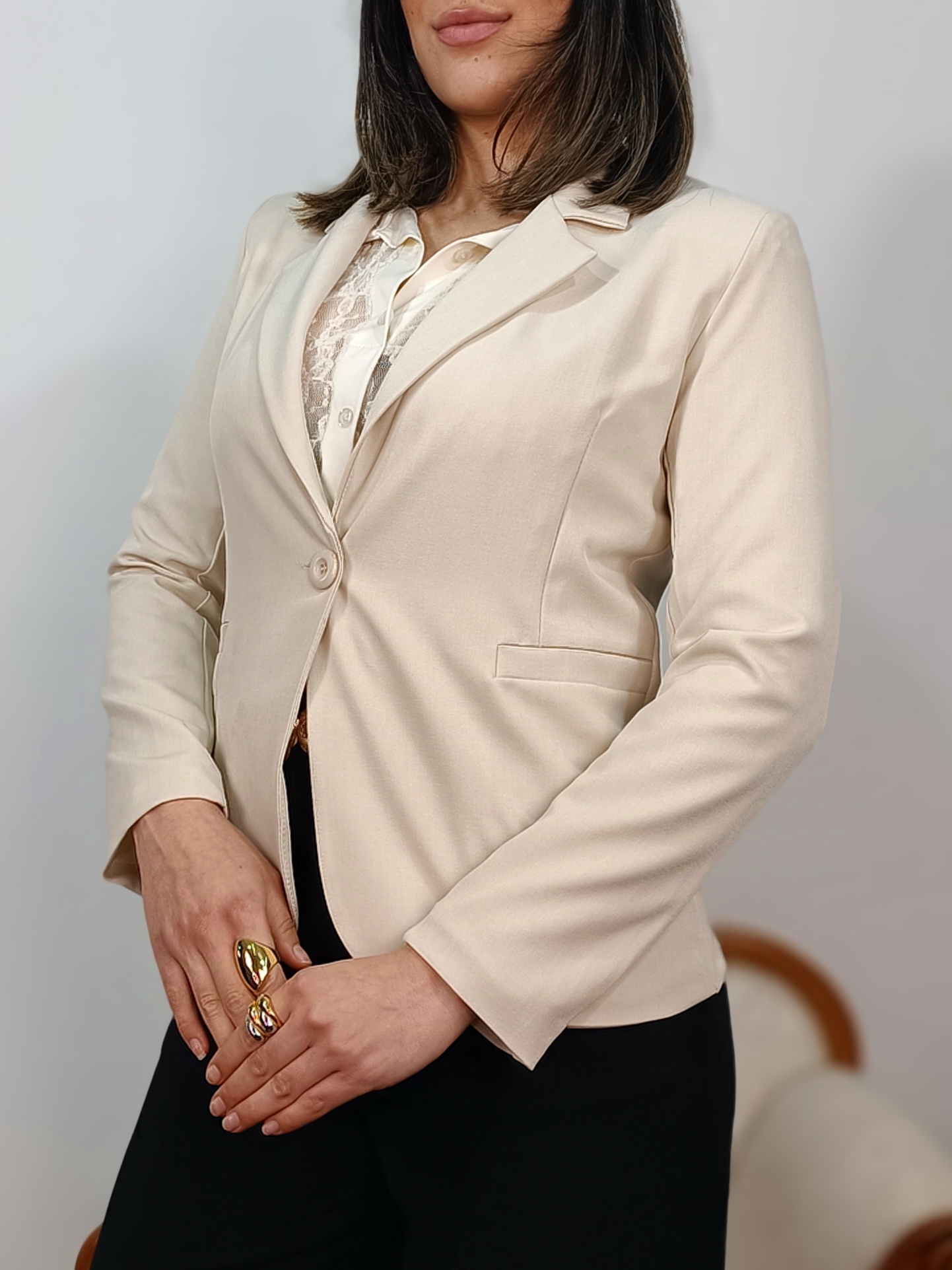 Perfil de la americana sastre beige resaltando la estructura del hombro y manga.