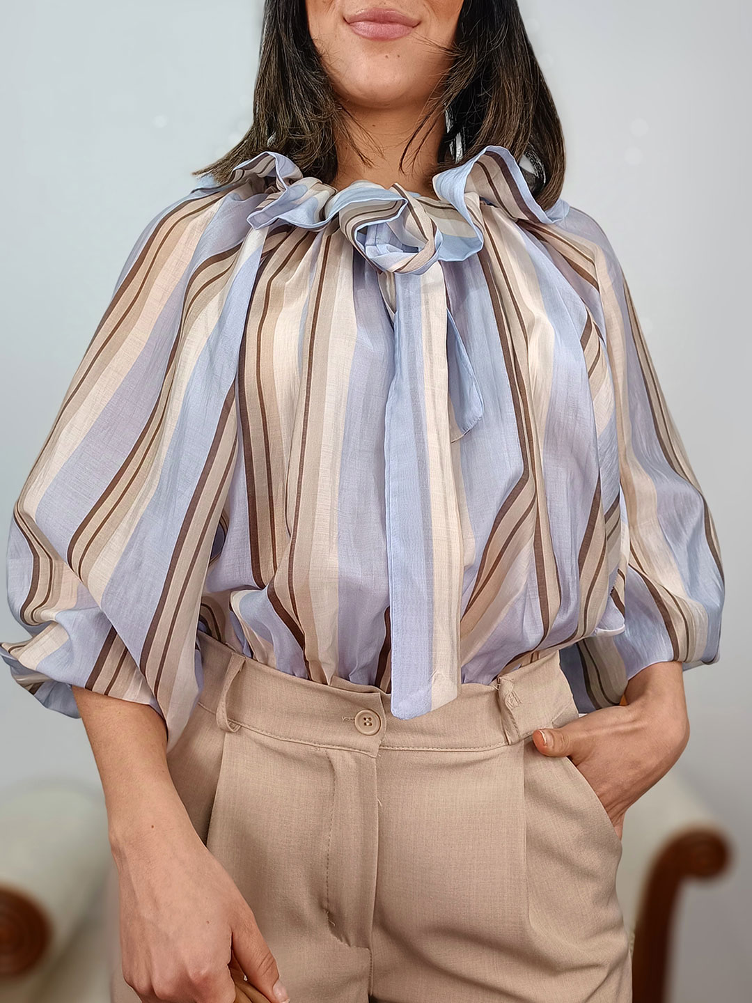 Primer plano del cuello con volantes y lazada de la blusa de rayas azul