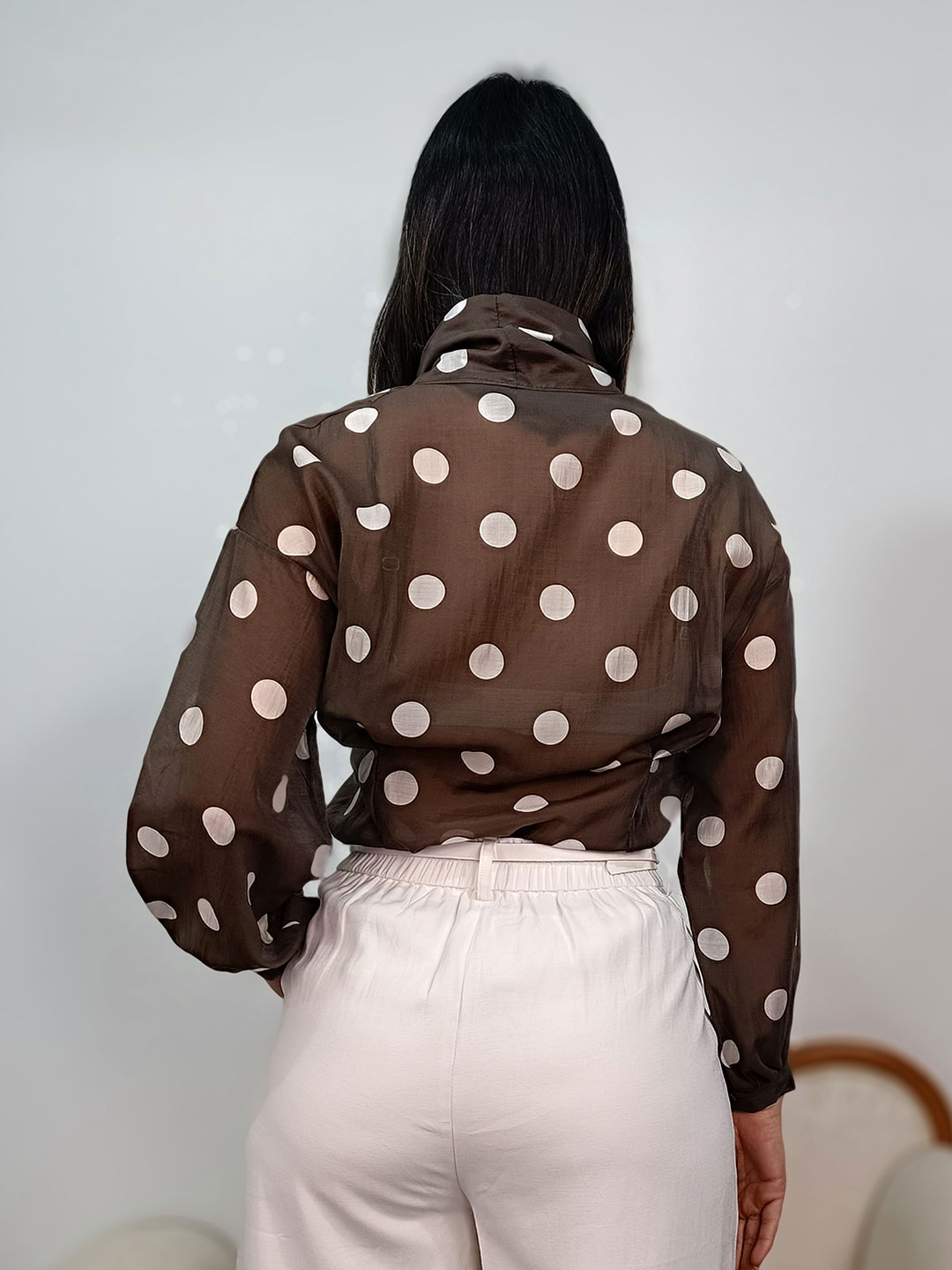 Espalda de la blusa marrón de lunares con caída fluida.