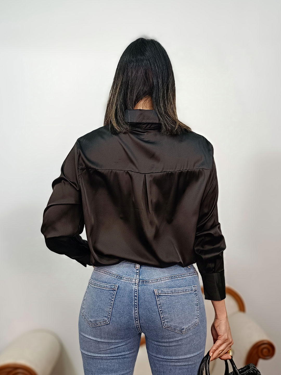 Vista trasera de camisa satinada negra de manga larga con caída fluida