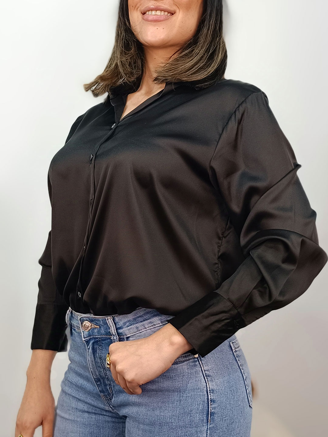 Perfil de la camisa satinada negra resaltando la caída de la manga.