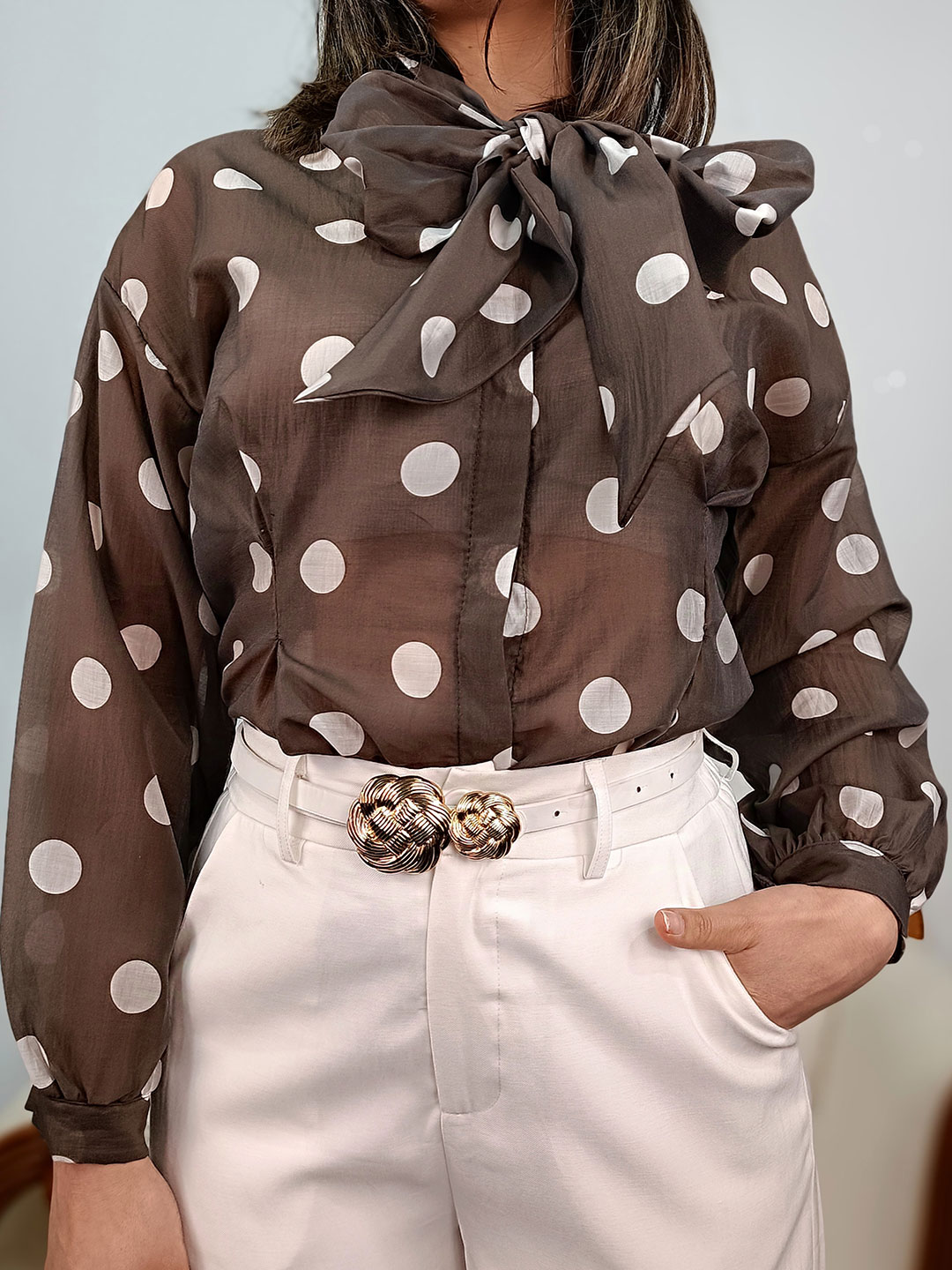 Primer plano del tejido y lazo de la blusa marrón lunares blancos lazo