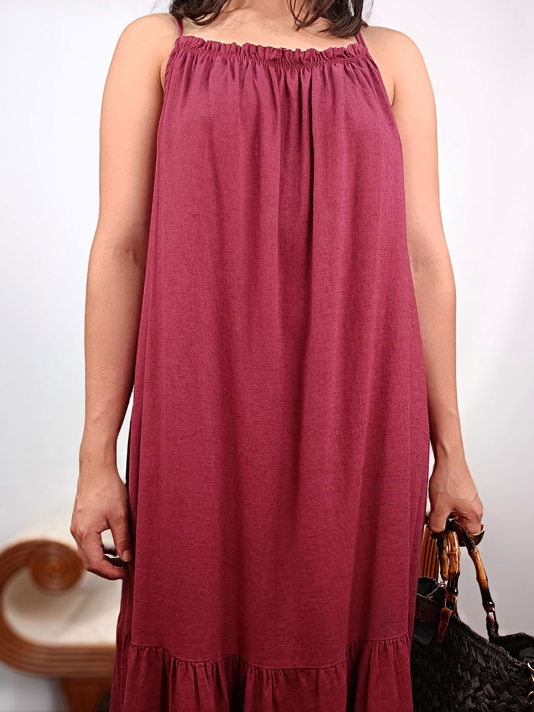 Detalle de escote halter fruncido en vestido fluido de color vino